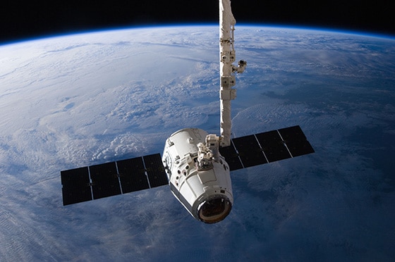ISSのロボットアームにより、第2結合部（ハーモニー）の地球側ポートから取り外され、放出ポイントへ移動されたドラゴン補給船試験機2号機の写真